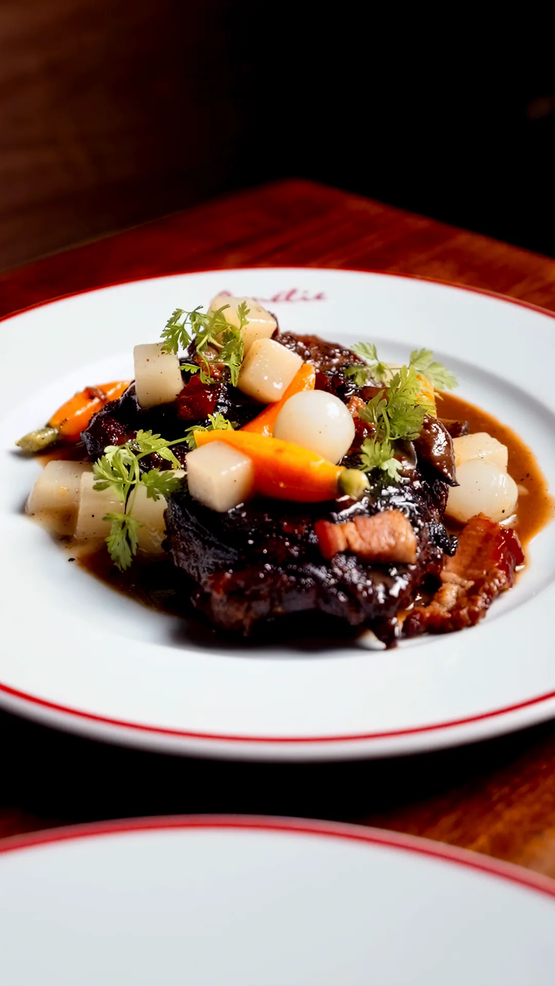 Coq au vin with turned carrots, pearl onions and lardons in a dark wine sauce, shot from above