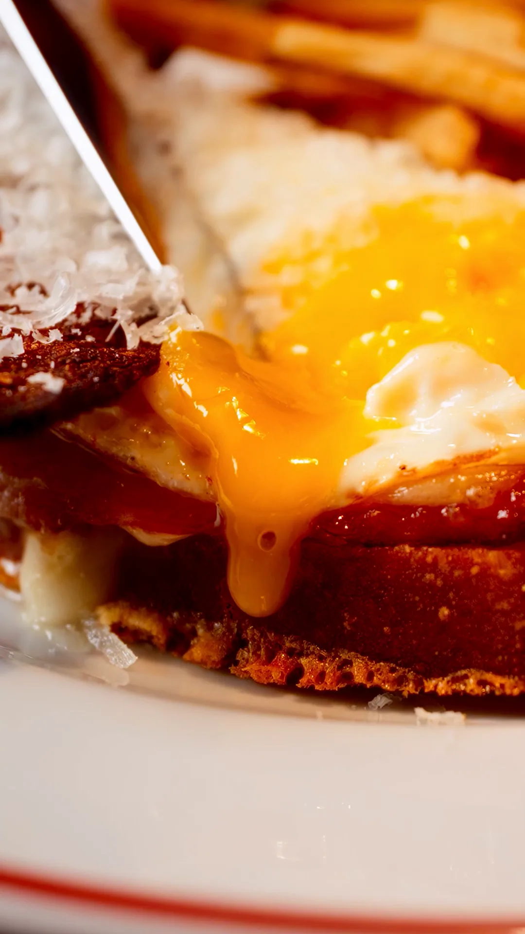 A croque monsieur under a blanket of melted cheese, a soft egg yolk breaking over the side