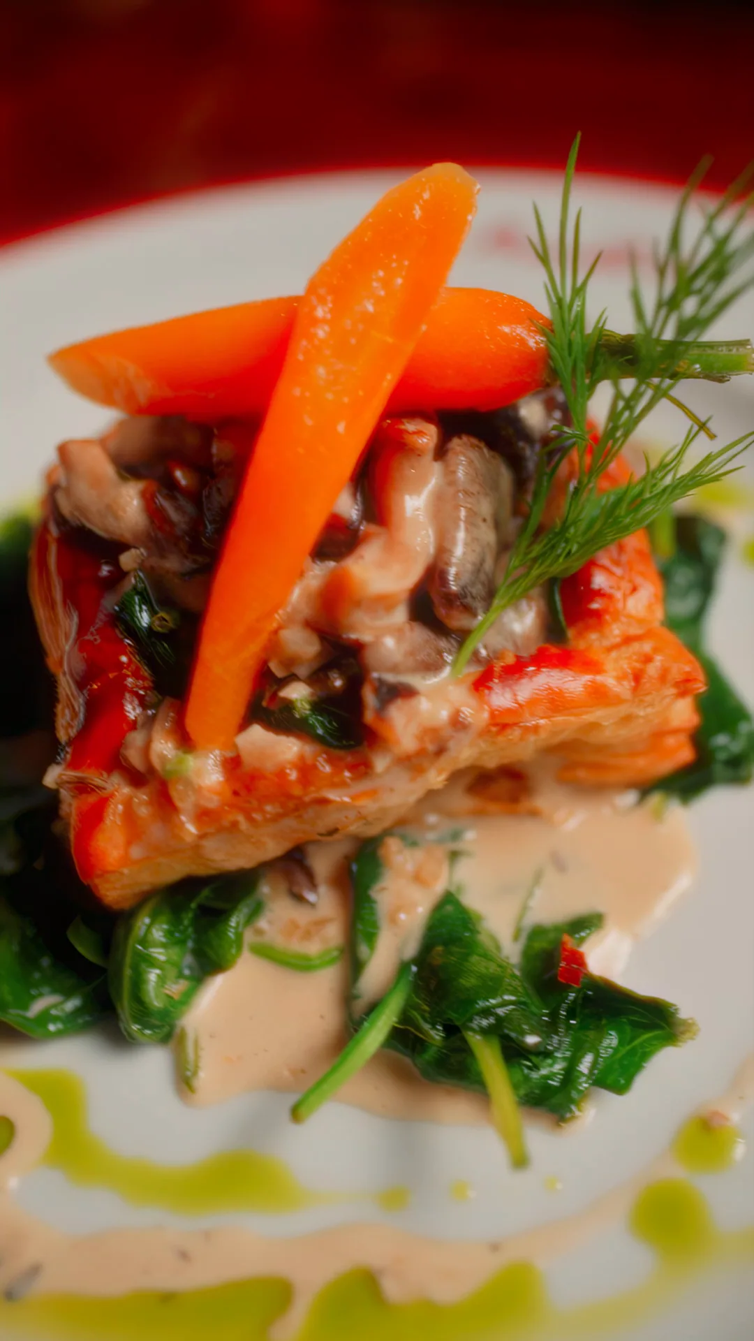 A vol-au-vent of puff pastry in cream sauce over wilted spinach, finished with a glazed carrot and dill