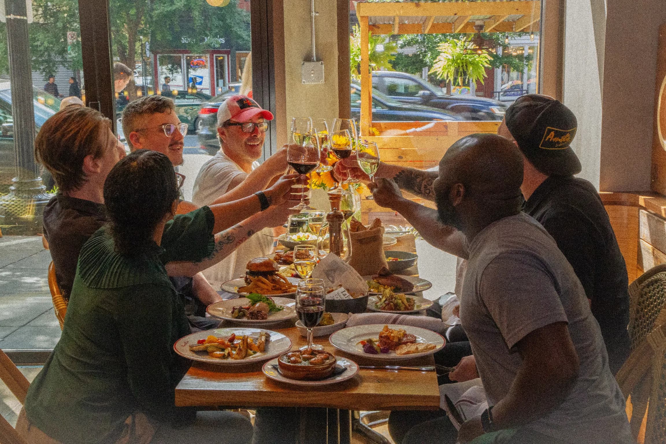 A group of guests raising their glasses over lunch at the window at Amélie Washington D.C.